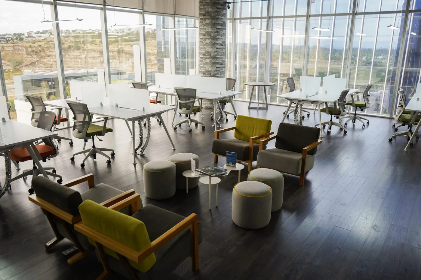 Área común de GPD Antea con estaciones de trabajo y sillones frente al ventanal, Querétaro