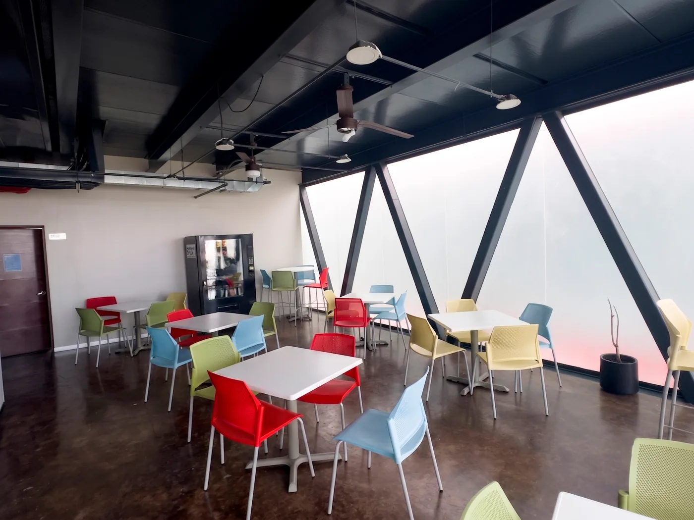Comedor de GPD Central Park con ventanales y mobiliario de colores, Querétaro